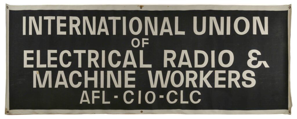 A long horizontal banner with a black background, white edges and text, six small metal circles in the corners and midpoints of the long edges, text reads union name and affiliations