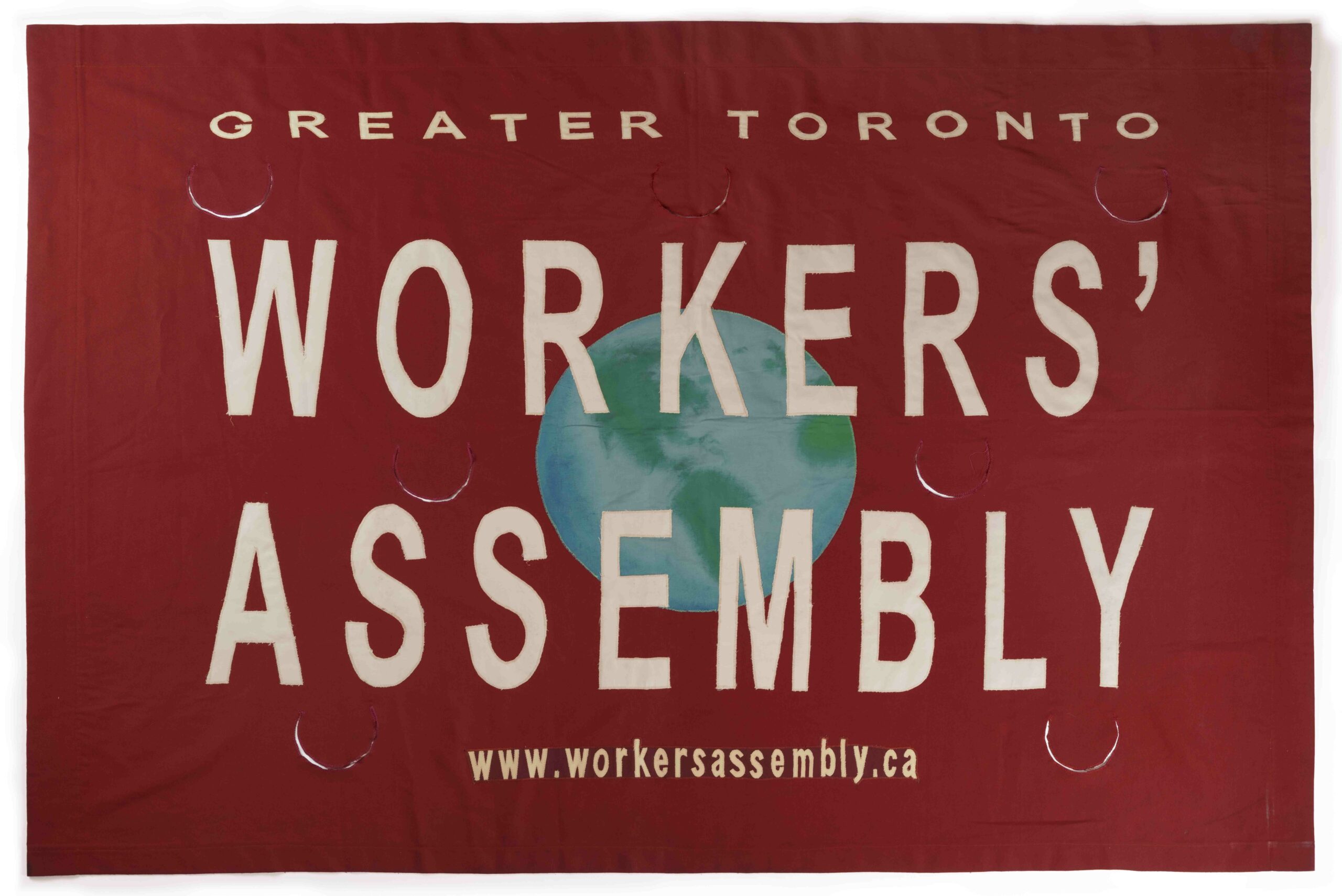 Large red banner with an illustration on the Earth in the middle, text across the width of the banner reads GREATER TORONTO WORKERS' ASSEMBLY, www.workersassembly.ca