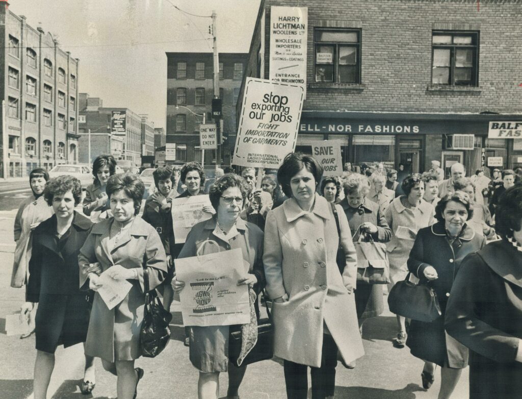 Black and white photo of women demonstrating in the street, some are holding placards